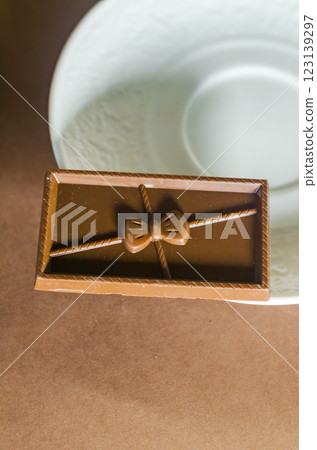 Elegant chocolate bar with bow design placed on a decorative plate, close-up. High quality photo 123139297