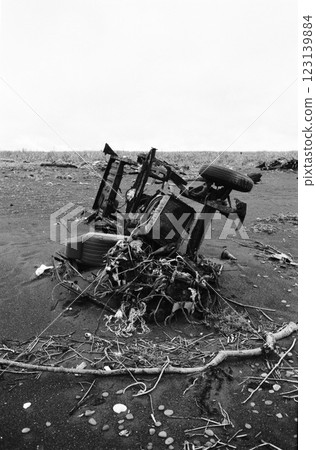 Abandoned car chassis on the beach, black and white image 123139884