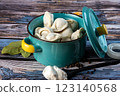 Raw dumplings in a blue bowl on a wooden background. 123140568