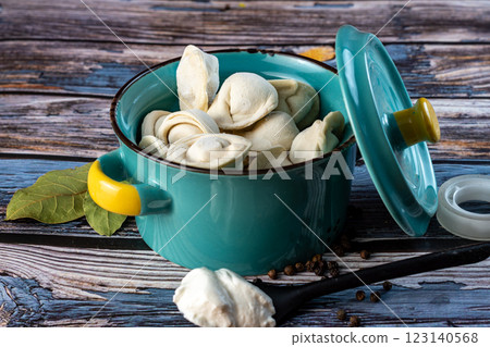 Raw dumplings in a blue bowl on a wooden background. Raw dumplings in a blue bowl on a wooden background. 123140568