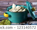 Raw dumplings in a blue bowl on a wooden background. 123140572
