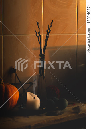 Atmospheric witchy home altar at sunrise indoor. Extinguished candle, willow branches in a glass vase, magic items on a shelf, vertical format. 123140574