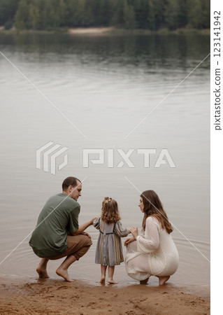 Family spending quality time by a calm lake.  123141942