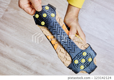 Crampons with yellow metal spikes and rubber base are securely fitted to hiking boot, enhancing stability in winter conditions. Crampons with yellow metal spikes and rubber base are securely fitted to hiking boot, enhancing stability in winter conditions. 123142124