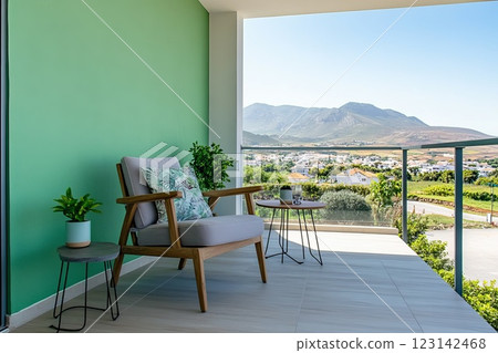 Open wide terrace in pastel mint tones, armchair and table near green wall, view of distant mountain landscape 123142468