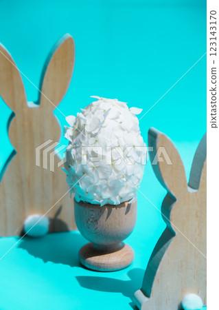 Creative Easter egg shape made of white lilac spring petals flowers. Responsible holidays decoration wooden rabbit bunny decor. Minimal holiday concept still life. Copy space 123143170