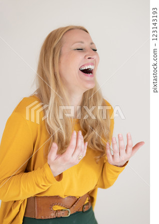 Portrait of confident beautiful woman laughing, with long blende hair, wearing casual clothes, standing in welcoming pose with open hands, meditating. Portrait of confident beautiful woman laughing, with long blende hair, wearing casual clothes, standing in welcoming pose with open hands, meditating. 123143193