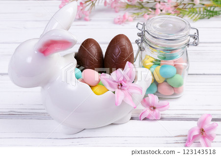 Easter bunny and jar with chocolate eggs, pink flowers. Easter bunny and jar with chocolate eggs, pink flowers. 123143518