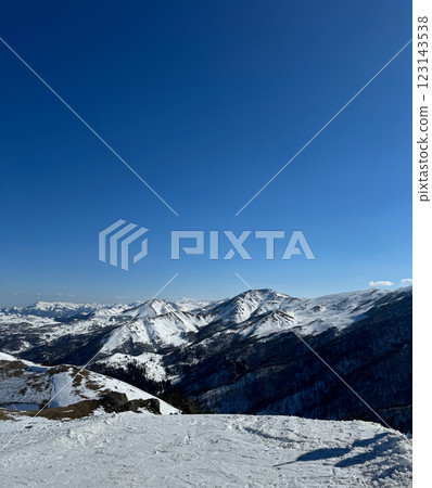 Vertical aerial view of the snow-covered mountain peaks in Bakuriani, Georgia, clear blue sky, with space for text, for cards and banner 123143538