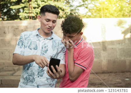 A young man explaining with his cell phone to a young man, A young man showing his cell phone to another young man 123143781