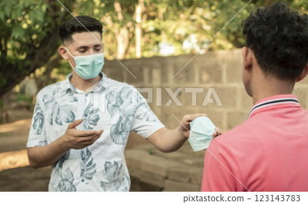 young man sharing mask to another young man, young man giving a mask to another young man, concept of giving a mask, young man sharing mask to another young man, young man giving a mask to another young man, concept of giving a mask, 123143783