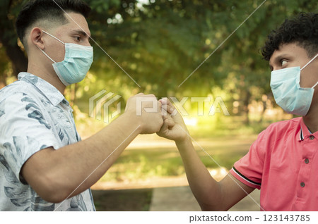 Two young men clashing their fists, image of two young men bumping their fists in a friendly way, close up of two fists bumping in a friendly way 123143785