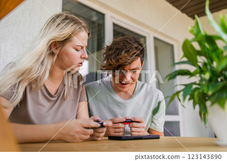 Joyful man and woman playing video games on terrace. Technology and game console concept 123143890