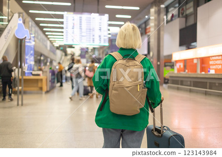 Caucasian senior woman passengers with suitcase using mobile phone booking hotel during waiting flight at boarding gate in airport terminal. Attractive female tourist travel by airplane on holiday Caucasian senior woman passengers with suitcase using mobile phone booking hotel during waiting flight at boarding gate in airport terminal. Attractive female tourist travel by airplane on holiday 123143984