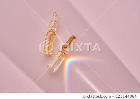An ampoule with a medical product or cosmetic product on a pink background. 123144064