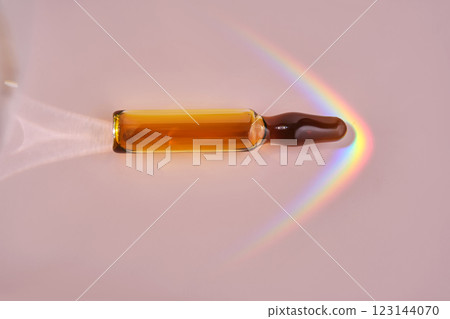 An ampoule with a medical product or cosmetic product on a pink background. 123144070