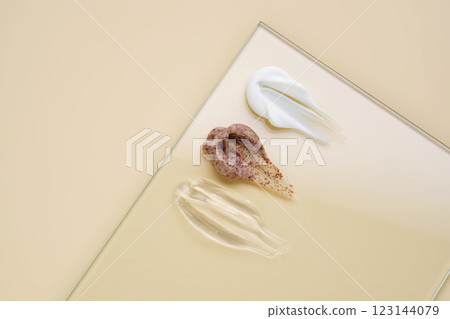 A smears of white cream, hyaluronic gel and coffee cream scrub on a beige background. A smears of white cream, hyaluronic gel and coffee cream scrub on a beige background. 123144079