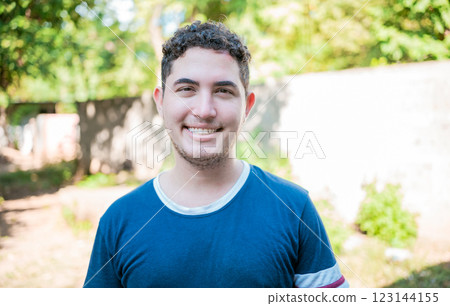 Portrait of Latin American man looking and smiling at the camera. Portrait of cheerful young latin guy smiling at camera outdoors 123144155