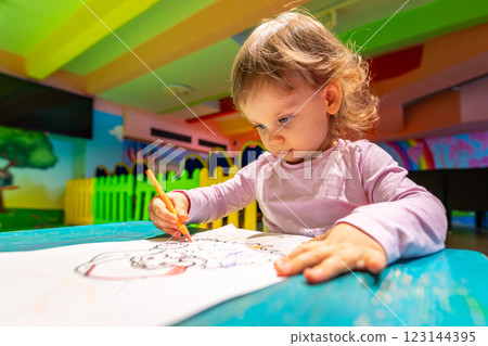 Toddler deeply focused on drawing in a vibrant and playful creative space. Toddler deeply focused on drawing in a vibrant and playful creative space. 123144395