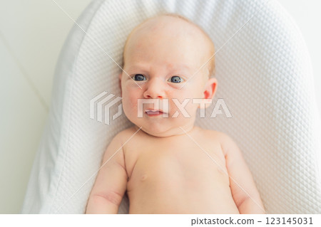 Adorable baby lying safely in a cozy infant cocoon. Comfortable and protective design for newborn care. Parenting, safety, and baby comfort concept 123145031