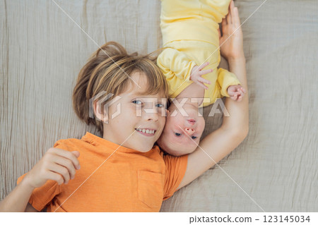 A young boy and his newborn brother lie together on a soft muslin blanket, sharing a tender sibling moment. A heartwarming scene of brotherly love, bonding, and the beginning of a lifelong connection A young boy and his newborn brother lie together on a soft muslin blanket, sharing a tender sibling moment. A heartwarming scene of brotherly love, bonding, and the beginning of a lifelong connection 123145034