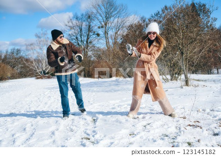 Couple enjoying a playful snowball fight in a winter landscape Couple enjoying a playful snowball fight in a winter landscape 123145182