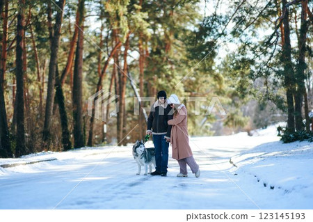 Couple enjoying a winter walk with a dog in a snowy forest 123145193