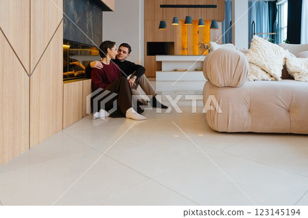 Couple enjoys cozy moment in modern living room with fireplace 123145194
