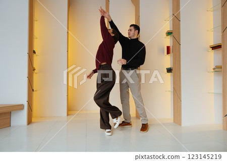 Couple dancing gracefully in a modern indoor space during daytime Couple dancing gracefully in a modern indoor space during daytime 123145219