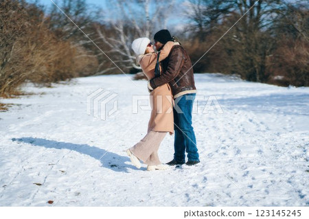 Couple embracing in winter wonderland snow-covered park Couple embracing in winter wonderland snow-covered park 123145245