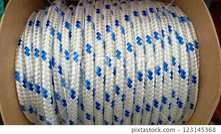 A coiled rope that features white and blue colors neatly placed within a sturdy cylinder 123145368