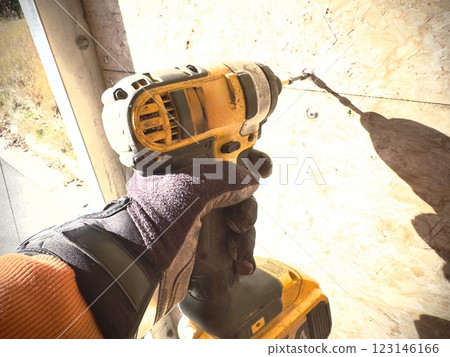 a worker in a glove tightens a screw using a screwdriver a worker in a glove tightens a screw using a screwdriver 123146166