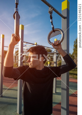 young athletic man resting after fitness calisthenics workout at street gym during sunset, taking a break during body improvement and strength training young athletic man resting after fitness calisthenics workout at street gym during sunset, taking a break during body improvement and strength training 123146821