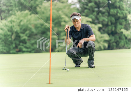 Male golfer reading the lines on the golf course green 123147165