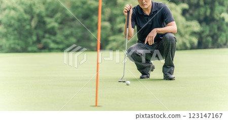 Male golfer reading the lines on the golf course green 123147167