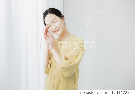 A woman by the window feeling the moisture in her skin A woman by the window feeling the moisture in her skin 123147235