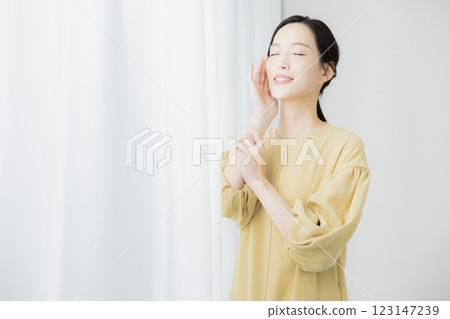 A woman by the window feeling the moisture in her skin A woman by the window feeling the moisture in her skin 123147239