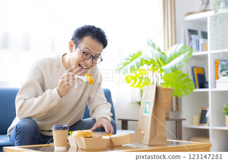 A man eating food he ordered via delivery service A man eating food he ordered via delivery service 123147281