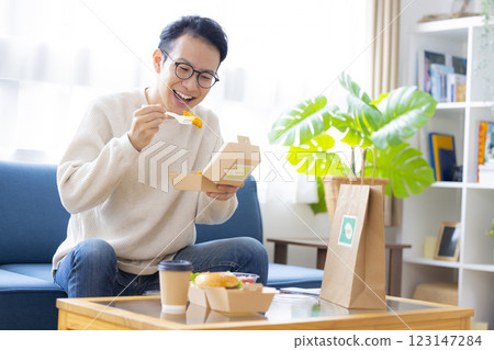 A man eating food he ordered via delivery service A man eating food he ordered via delivery service 123147284