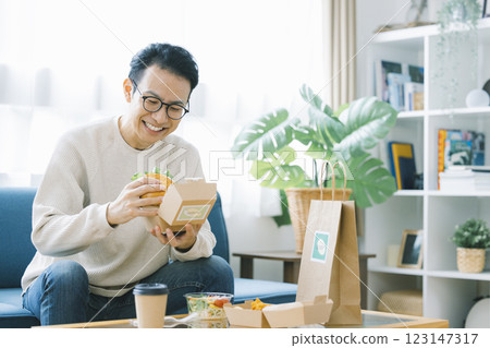 一名男子正在吃外送訂購的食物 一名男子正在吃外送訂購的食物 123147317