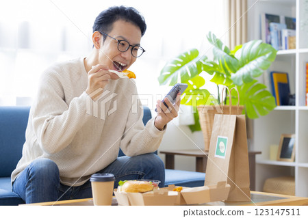 一名男子正在吃外送訂購的食物 123147511