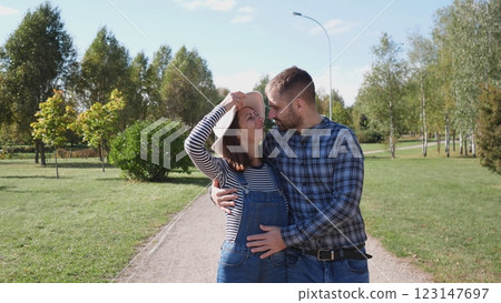 A loving couple shares a very tender and affectionate moment in a lush park under bright blue skies above A loving couple shares a very tender and affectionate moment in a lush park under bright blue skies above 123147697