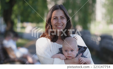 Joyful mom holding a small child in her arms portrait in summer in the park 123147754