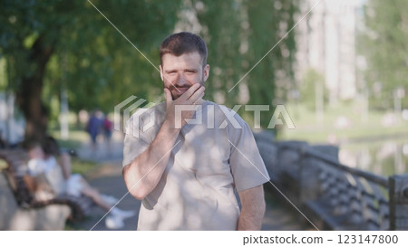 A man dressed in casual attire is lost in deep thought while being surrounded by nature in a tranquil park A man dressed in casual attire is lost in deep thought while being surrounded by nature in a tranquil park 123147800