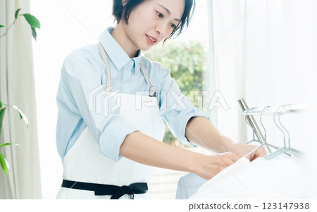 一名婦女將衣服掛在室內晾乾 123147938