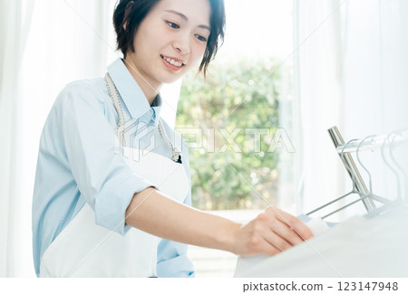 一名婦女將衣服掛在室內晾乾 123147948