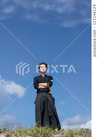 A young man in a kendo uniform with his arms folded under the blue sky A young man in a kendo uniform with his arms folded under the blue sky 123148129