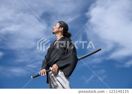 A middle-aged man in kimono standing with a sword 123148135