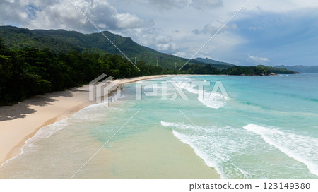 White sandy beach meets turquoise waves, surrounded by tropical vegetation and greenery. Seychelles, Mahe. Grand Anse Beach. 123149380