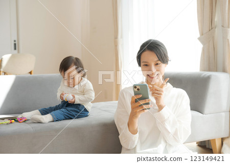 Mom looking at smartphone and girl playing with toys Mom looking at smartphone and girl playing with toys 123149421